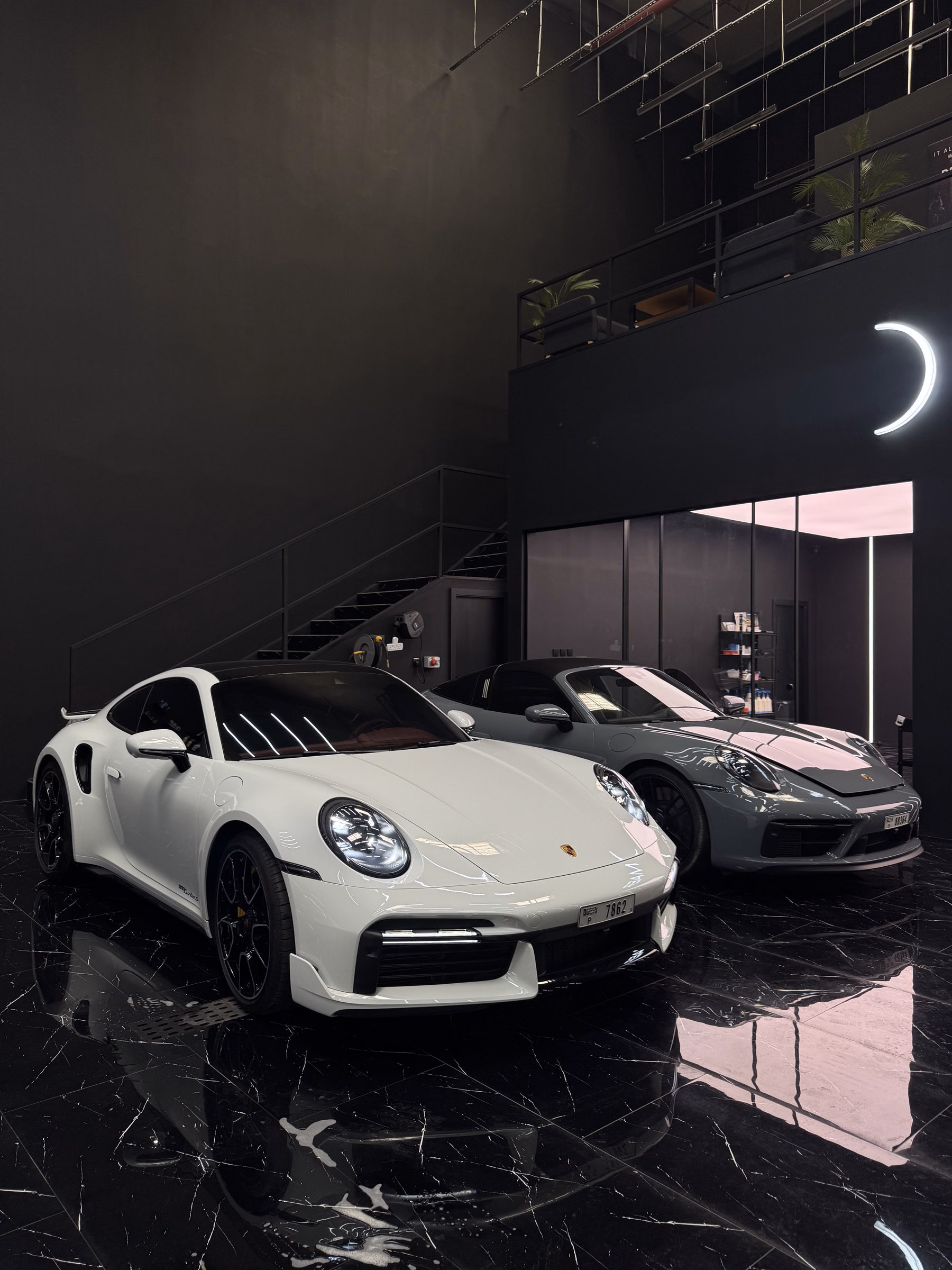 A white and a grey Porsche 911 photographed from the front after paint correction and full body paint protection film